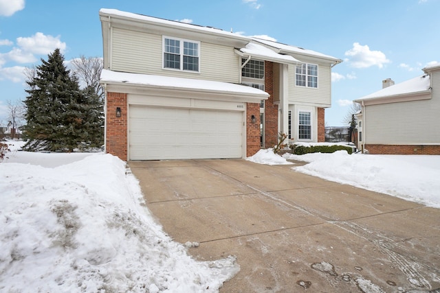 traditional-style home featuring a garage, brick siding, and driveway