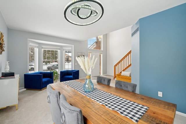 dining area with baseboards, stairs, visible vents, and light colored carpet