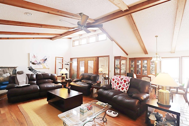 living room featuring a healthy amount of sunlight, beamed ceiling, a textured ceiling, and wood finished floors