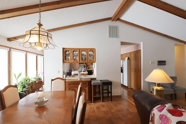 dining area featuring dark wood-type flooring, a chandelier, a textured ceiling, and vaulted ceiling with beams