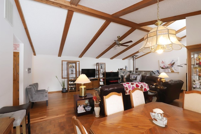 dining room with lofted ceiling with beams, ceiling fan with notable chandelier, wood finished floors, and visible vents