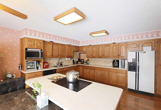 kitchen with dark wood-type flooring, sink, a textured ceiling, a kitchen island, and black appliances