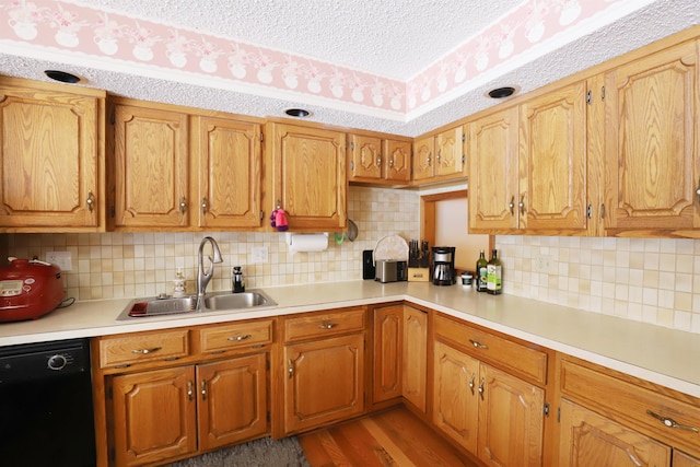 kitchen with dishwasher, brown cabinets, light countertops, a textured ceiling, and a sink