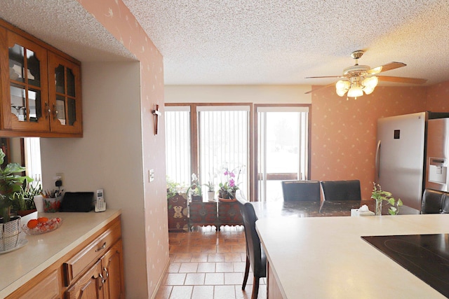 kitchen featuring ceiling fan, stainless steel fridge, a textured ceiling, and black stovetop