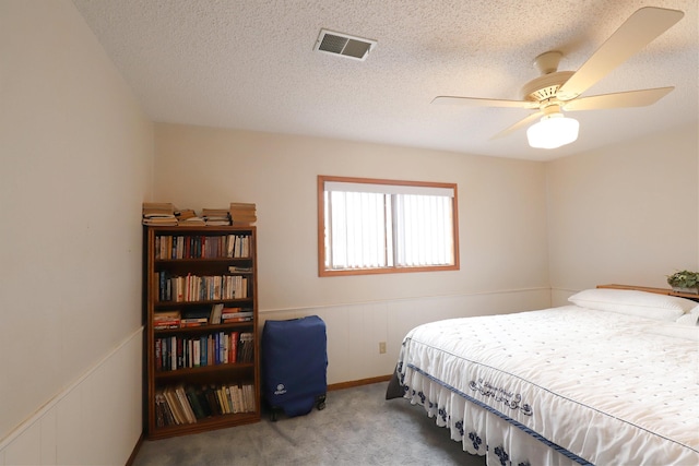 carpeted bedroom featuring ceiling fan and a textured ceiling