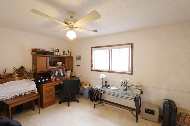 home office with a textured ceiling, light carpet, a ceiling fan, and wallpapered walls