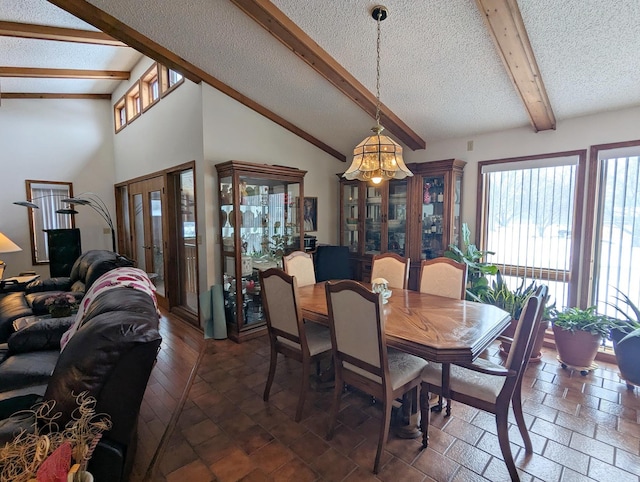 dining room with a textured ceiling, high vaulted ceiling, french doors, and beam ceiling