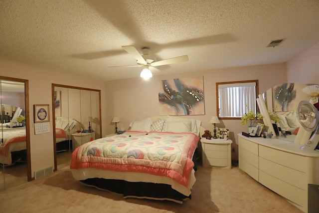 bedroom with light carpet, ceiling fan, a textured ceiling, and visible vents