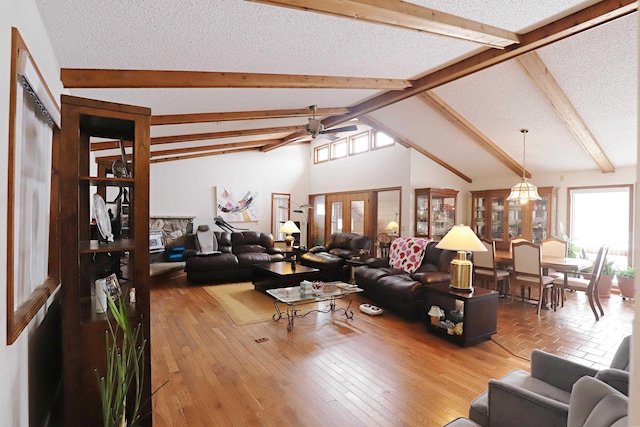 living area with a textured ceiling, ceiling fan, beam ceiling, and wood finished floors