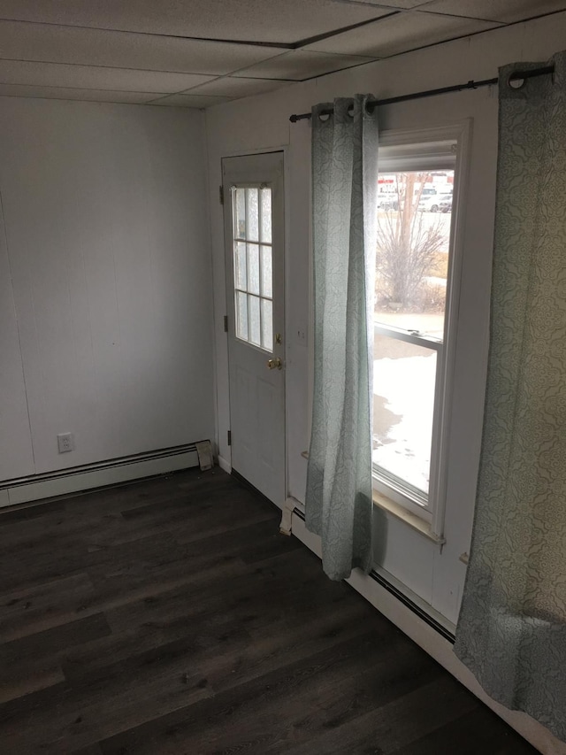 empty room featuring dark wood-type flooring, a wealth of natural light, and baseboard heating