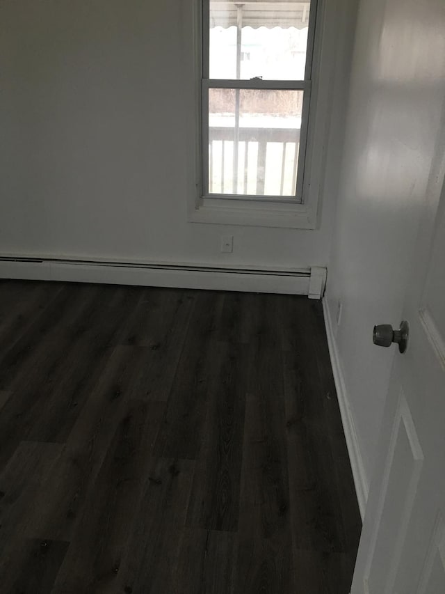 unfurnished room with a baseboard radiator and dark wood-type flooring