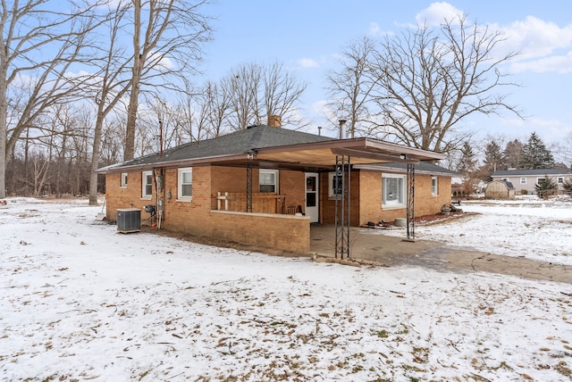 snow covered house featuring central AC