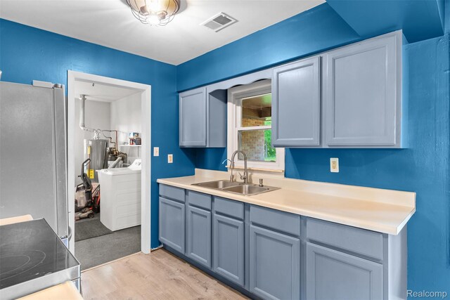 1408 Stephens Ave, Flint, MI 48507 - kitchen with freestanding refrigerator, light wood-style flooring, washing machine and clothes dryer, light countertops, and water heater