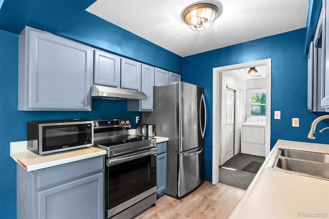 1408 Stephens Ave, Flint, MI 48507 - kitchen with stainless steel appliances, washer / dryer, under cabinet range hood, light wood finished floors, and light countertops