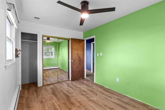 1408 Stephens Ave, Flint, MI 48507 - unfurnished bedroom featuring a baseboard heating unit, wood finished floors, and a ceiling fan