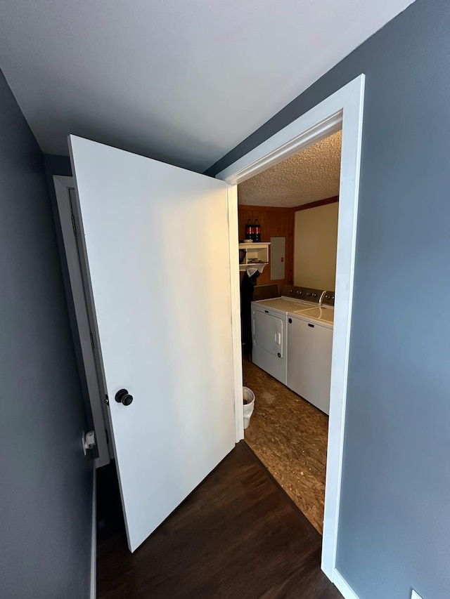 corridor featuring dark wood-type flooring, washing machine and clothes dryer, and a textured ceiling