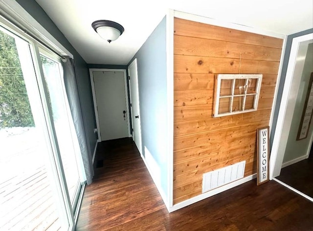 hallway with dark hardwood / wood-style flooring and wood walls