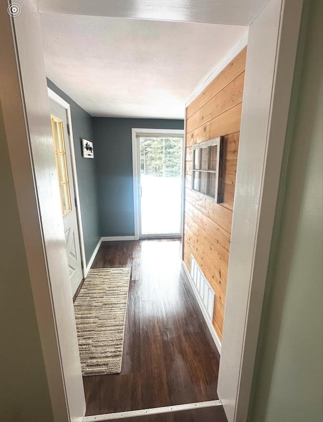 corridor with dark wood-type flooring and wooden walls