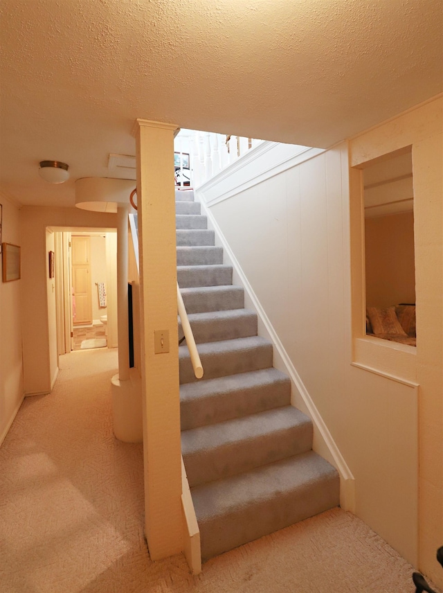 stairs featuring a textured ceiling and carpet