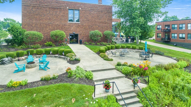 view of community with a patio area, a fire pit, and a lawn