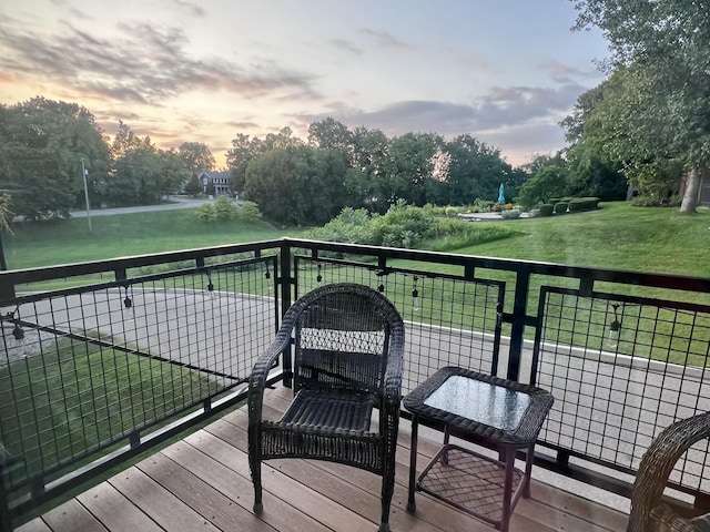 deck at dusk featuring a yard