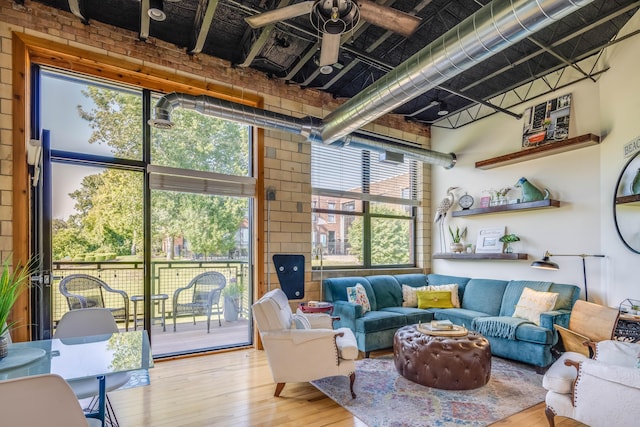 living room featuring hardwood / wood-style flooring, brick wall, and a towering ceiling