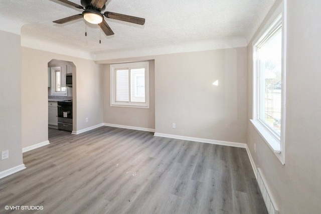 unfurnished living room featuring ceiling fan, a wealth of natural light, a textured ceiling, and light hardwood / wood-style floors