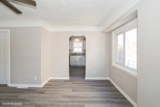 empty room with dark hardwood / wood-style flooring, ceiling fan, and a textured ceiling