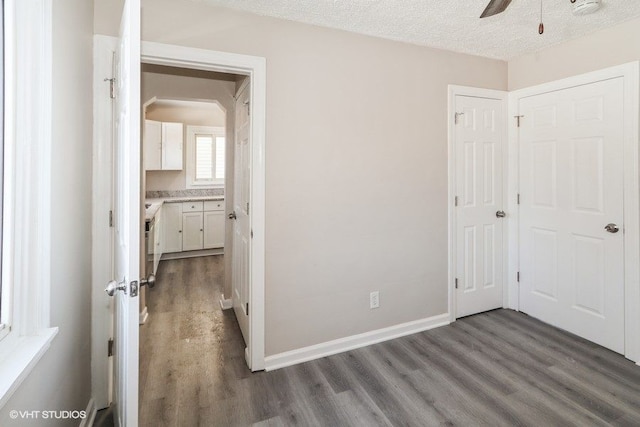 unfurnished bedroom featuring dark hardwood / wood-style flooring, ceiling fan, a closet, and a textured ceiling