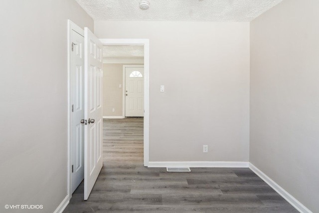 spare room featuring a textured ceiling and dark hardwood / wood-style flooring