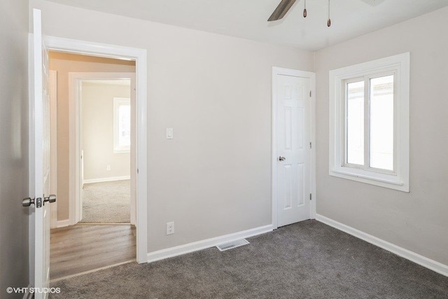 spare room with dark carpet and ceiling fan