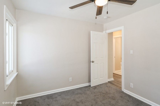 empty room with ceiling fan and dark carpet