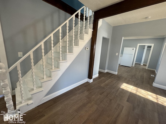 stairway featuring hardwood / wood-style flooring, a textured ceiling, and vaulted ceiling with beams