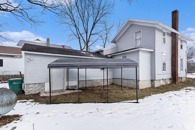 snow covered house featuring a carport