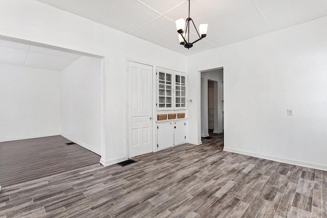 unfurnished dining area featuring an inviting chandelier and wood-type flooring