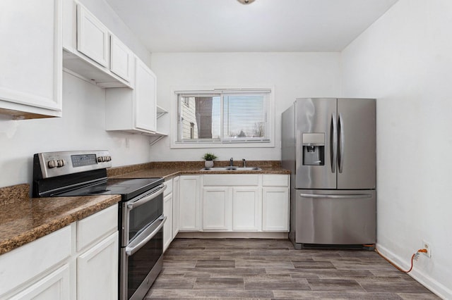 kitchen with dark hardwood / wood-style floors, sink, dark stone countertops, white cabinets, and stainless steel appliances