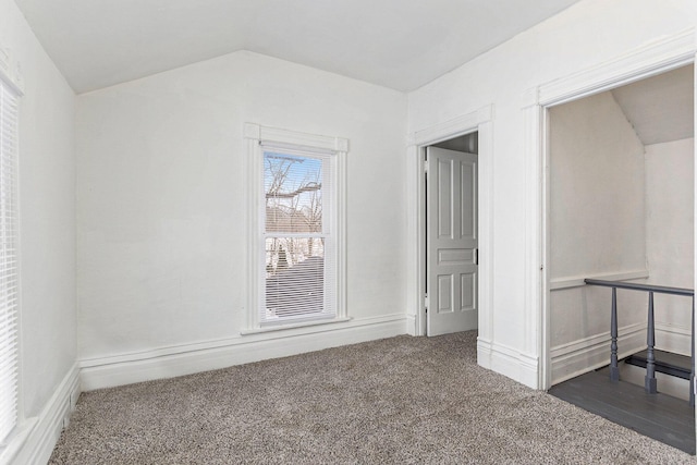 unfurnished room featuring lofted ceiling and dark carpet