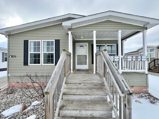 snow covered property entrance with covered porch