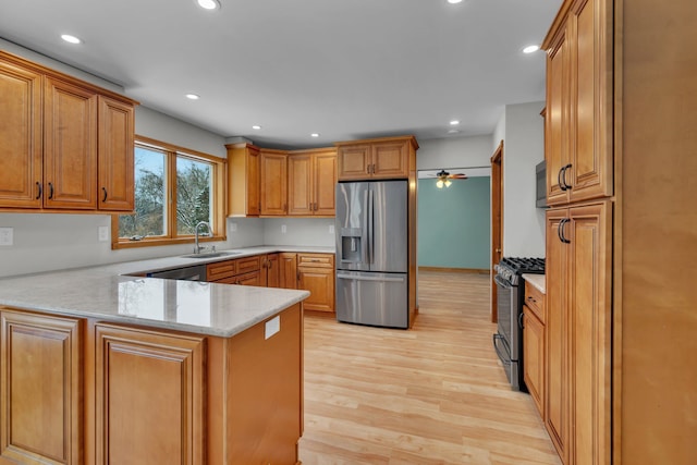 kitchen featuring appliances with stainless steel finishes, light stone counters, light hardwood / wood-style floors, sink, and kitchen peninsula