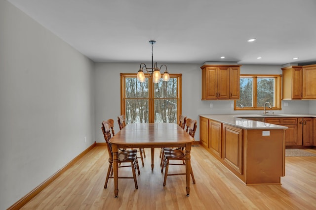 dining space featuring sink, a notable chandelier, and light hardwood / wood-style flooring