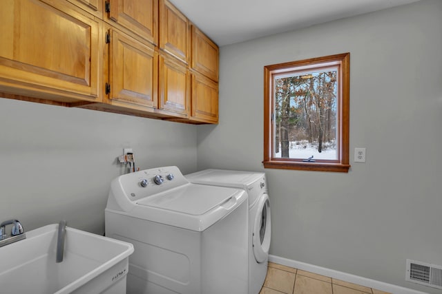 laundry area featuring washing machine and dryer, cabinets, sink, and light tile patterned flooring