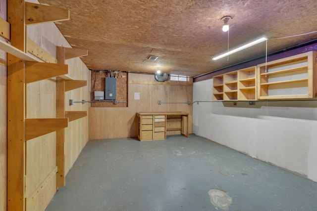 basement featuring electric panel and wood walls