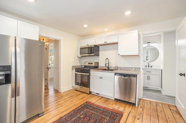 kitchen with light countertops, appliances with stainless steel finishes, light wood-type flooring, and white cabinets