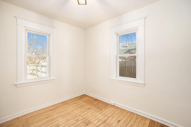 unfurnished room with light wood-type flooring, a wealth of natural light, and baseboards