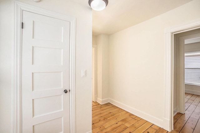 hallway featuring light wood-style flooring and baseboards