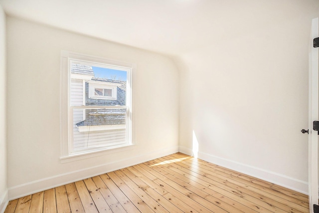 spare room with baseboards and light wood finished floors