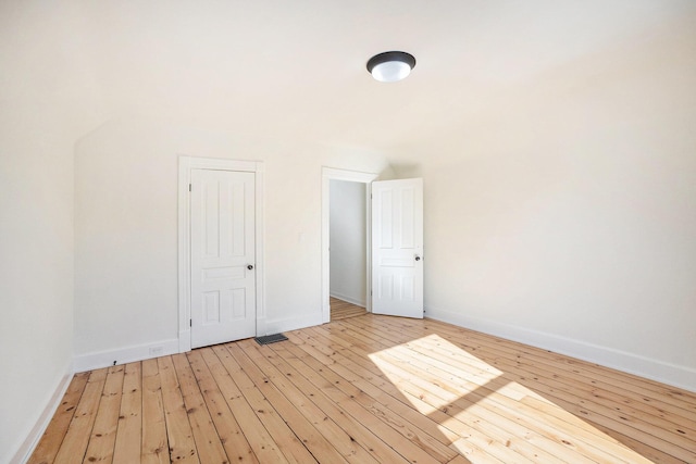 unfurnished room with light wood-type flooring, visible vents, and baseboards