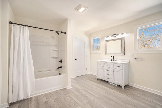 bathroom with plenty of natural light, shower / bathtub combination with curtain, and wood finished floors