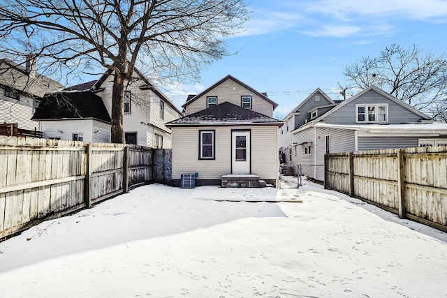 snow covered property featuring a fenced backyard and central AC