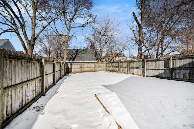 yard layered in snow with a fenced backyard